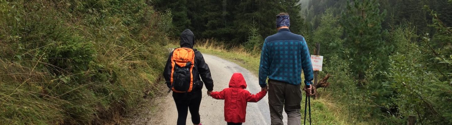 man, woman, and child walking together along dirt road