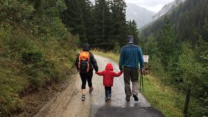 man, woman, and child walking together along dirt road